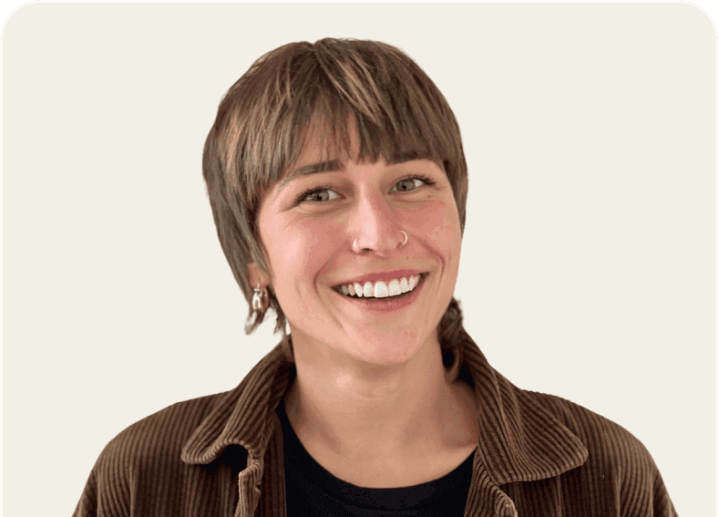 Smiling woman with short brown hair and bangs wearing a brown corduroy jacket.