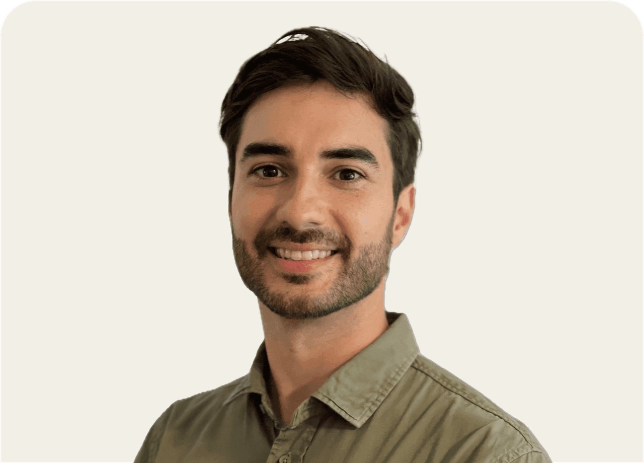 A smiling young man with short dark hair and a beard wearing a green shirt.